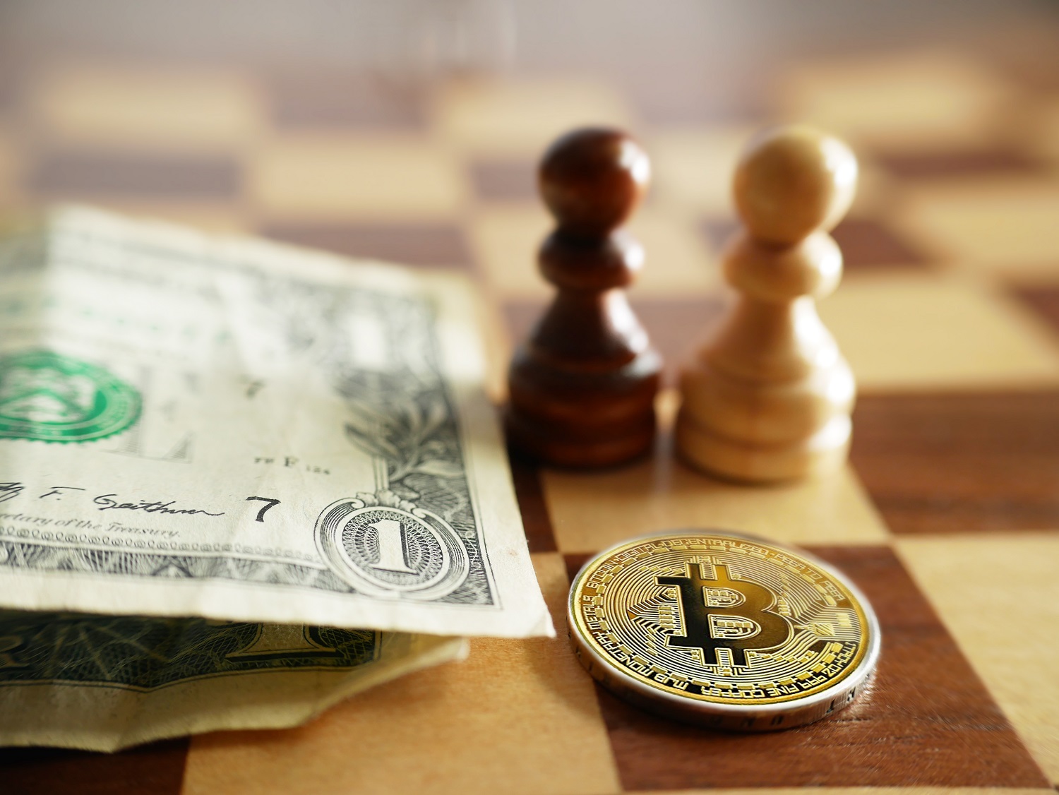 A metal token intended to represent Bitcoin next to US dollar bills on a chess board with chess pieces.